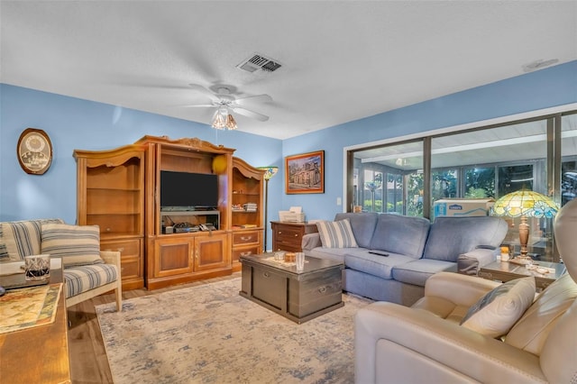 living area with ceiling fan, a textured ceiling, wood finished floors, and visible vents