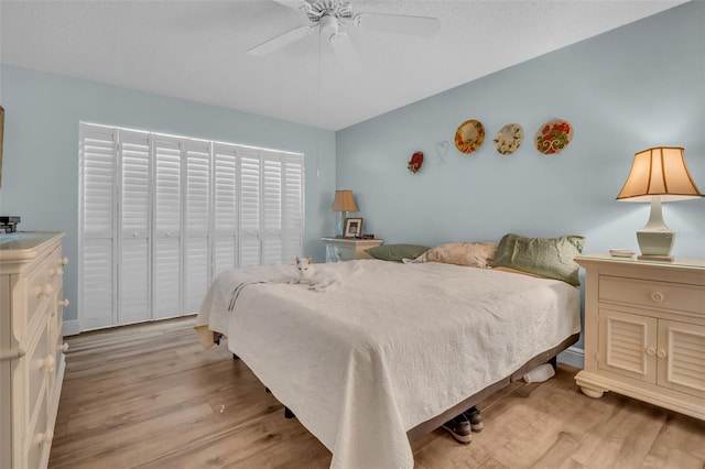 bedroom with light wood-style flooring, ceiling fan, and a textured ceiling