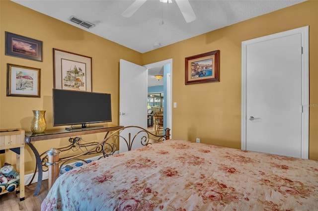 bedroom featuring a textured ceiling, wood finished floors, visible vents, and a ceiling fan