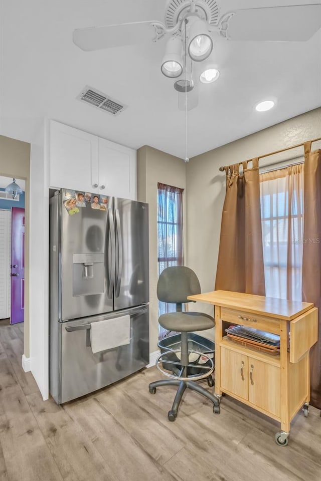 office space with light wood-style floors, visible vents, and baseboards