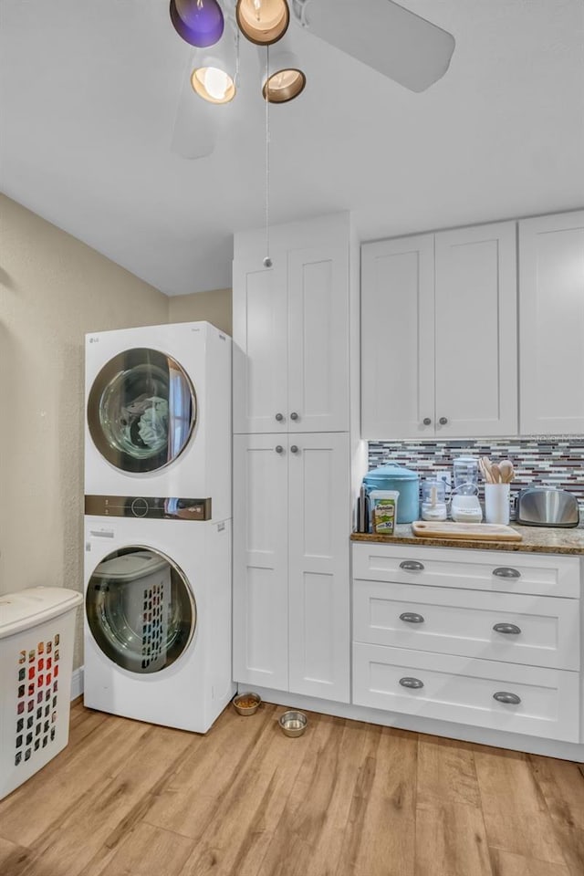 washroom featuring light wood-type flooring, stacked washer and clothes dryer, and laundry area