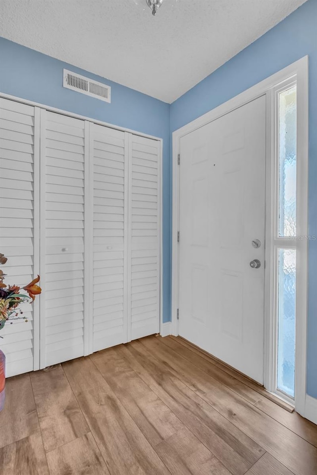 entryway with a textured ceiling, wood finished floors, and visible vents