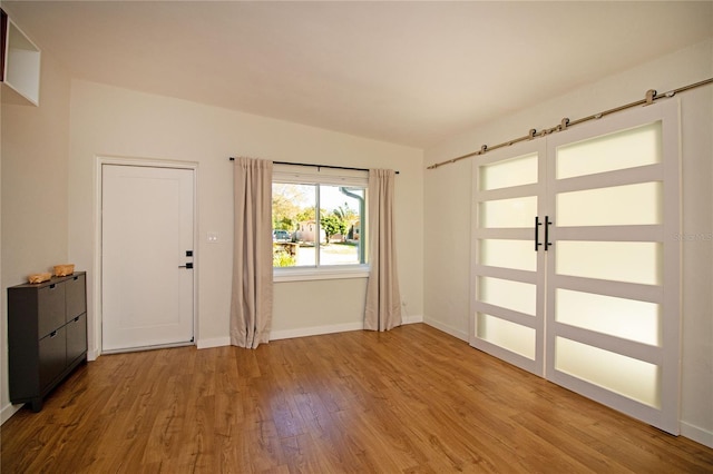 interior space featuring wood finished floors, baseboards, and a barn door