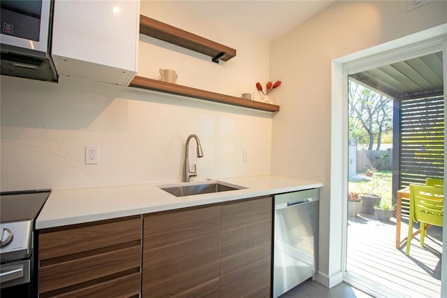 kitchen with a sink, light countertops, appliances with stainless steel finishes, open shelves, and modern cabinets