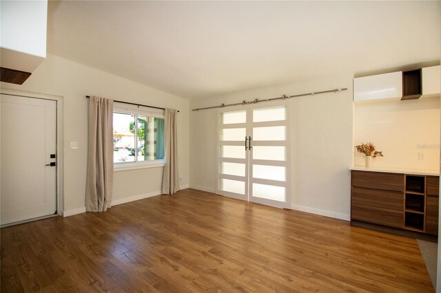 unfurnished living room with a wall mounted AC, baseboards, and wood finished floors