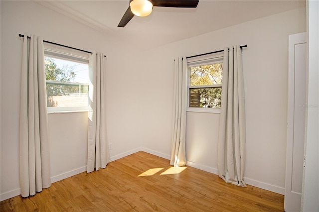 unfurnished room with light wood-style floors, a healthy amount of sunlight, ceiling fan, and baseboards