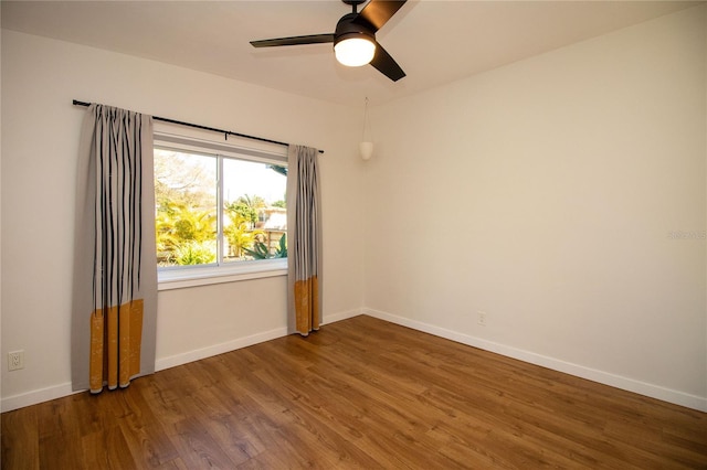 spare room featuring wood finished floors, a ceiling fan, and baseboards