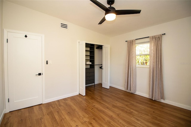 unfurnished bedroom featuring baseboards, visible vents, a ceiling fan, wood finished floors, and a closet