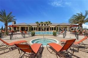 pool with a patio and a hot tub