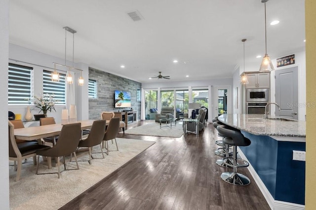 dining space featuring visible vents, a ceiling fan, an accent wall, dark wood-style flooring, and recessed lighting