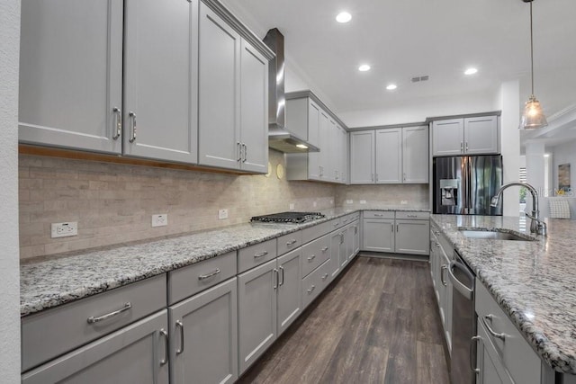 kitchen with gray cabinets, visible vents, appliances with stainless steel finishes, a sink, and wall chimney exhaust hood