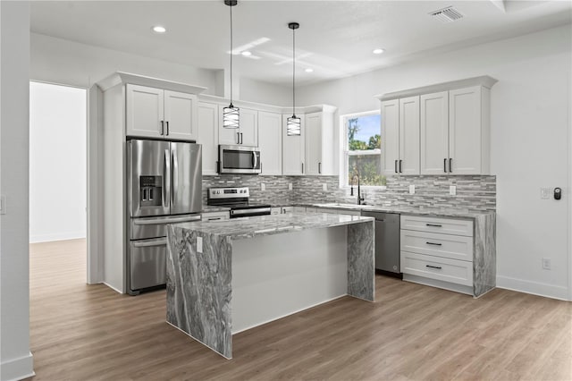 kitchen featuring appliances with stainless steel finishes, a kitchen island, visible vents, and decorative backsplash