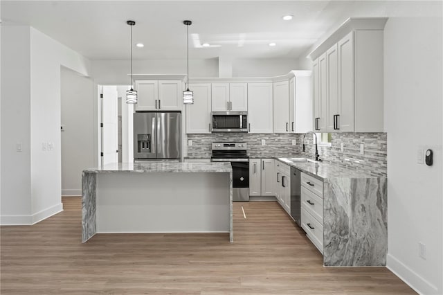 kitchen featuring appliances with stainless steel finishes, a kitchen island, a sink, and backsplash