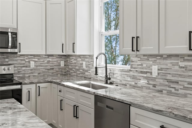 kitchen featuring stainless steel appliances, white cabinetry, and a sink