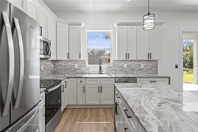 kitchen with light wood-style flooring, a sink, white cabinetry, appliances with stainless steel finishes, and backsplash