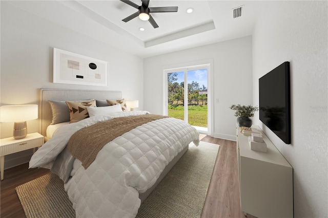 bedroom featuring recessed lighting, wood finished floors, visible vents, access to exterior, and a raised ceiling