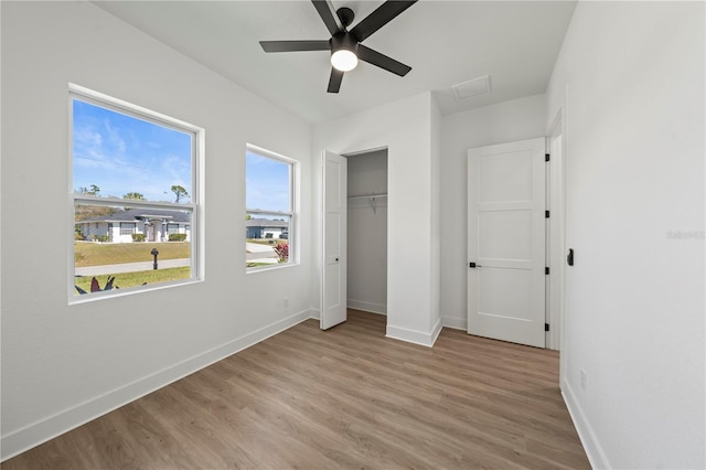 unfurnished bedroom with light wood-style floors, a closet, baseboards, and a ceiling fan