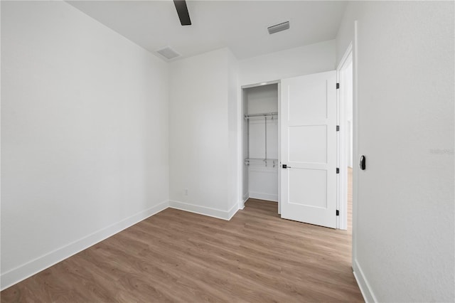 unfurnished bedroom featuring baseboards, a closet, visible vents, and wood finished floors