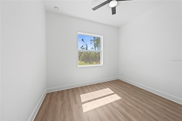 empty room with wood finished floors, a ceiling fan, and baseboards