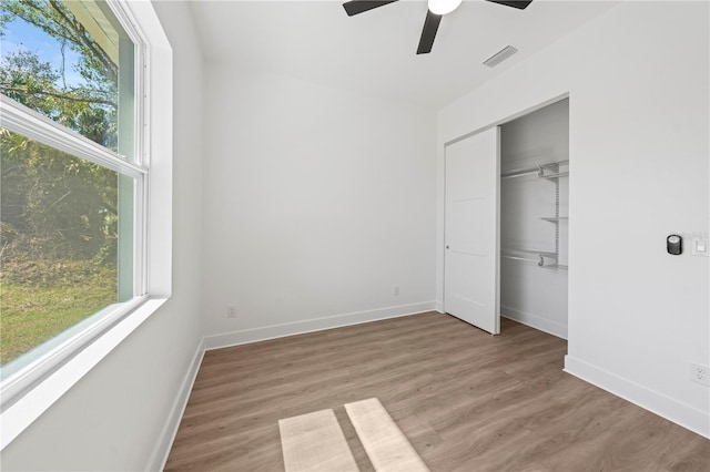 unfurnished bedroom with a closet, visible vents, ceiling fan, wood finished floors, and baseboards