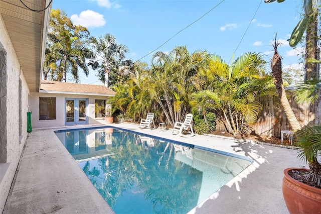 outdoor pool featuring french doors, a patio area, and fence