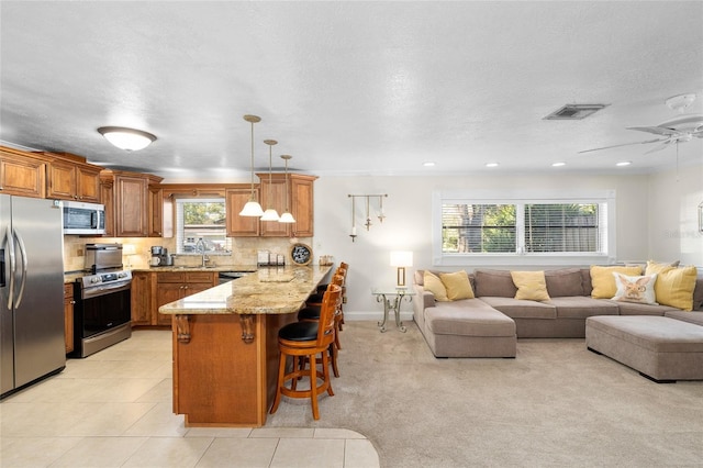 kitchen with a peninsula, appliances with stainless steel finishes, brown cabinets, and open floor plan