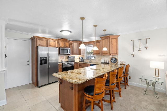 kitchen with light stone counters, stainless steel appliances, backsplash, brown cabinetry, and a peninsula