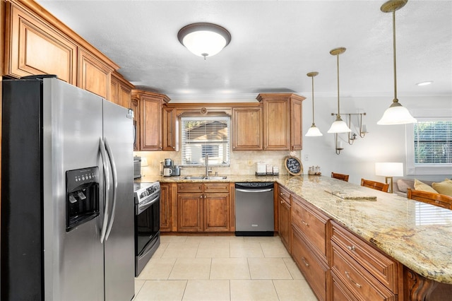 kitchen featuring a peninsula, appliances with stainless steel finishes, a sink, and brown cabinets