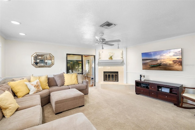 living area with a textured ceiling, a fireplace, visible vents, carpet, and crown molding