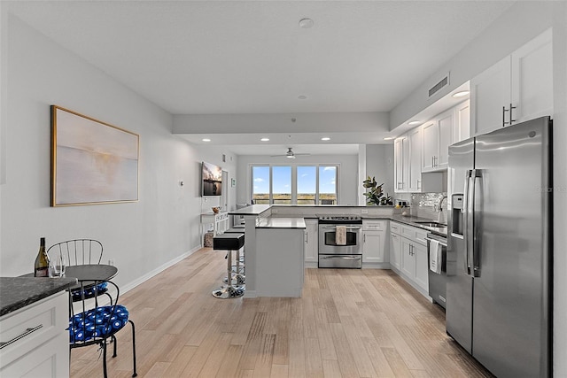 226 5th Ave N Unit 901, Saint Petersburg, FL 33701 - kitchen with stainless steel appliances, a sink, visible vents, light wood-style floors, and a kitchen bar