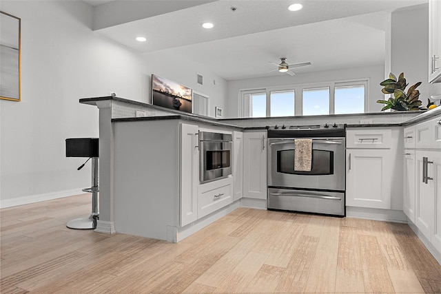 226 5th Ave N Unit 901, Saint Petersburg, FL 33701 - kitchen with electric stove, white cabinetry, ceiling fan, and light wood-style flooring