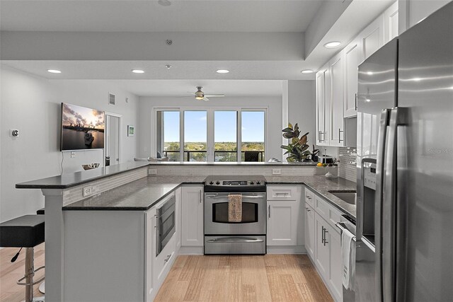 226 5th Ave N Unit 901, Saint Petersburg, FL 33701 - kitchen featuring appliances with stainless steel finishes, light wood-type flooring, white cabinetry, and a peninsula