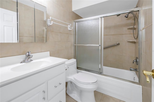 full bathroom featuring vanity, bath / shower combo with glass door, tile patterned flooring, tile walls, and toilet