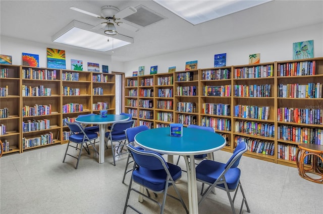 interior space featuring a ceiling fan and wall of books