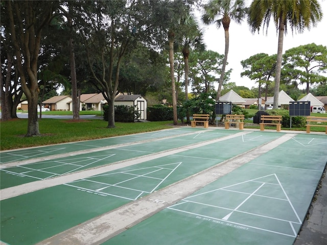 view of property's community with an outbuilding, shuffleboard, a lawn, and a shed