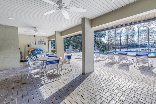 view of patio with a community pool, a ceiling fan, and fence