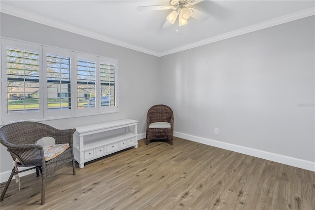 sitting room featuring a ceiling fan, crown molding, baseboards, and wood finished floors