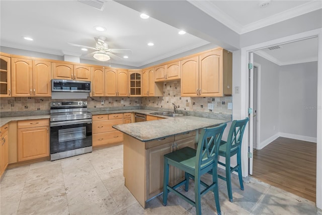 kitchen featuring light brown cabinetry, appliances with stainless steel finishes, glass insert cabinets, and a sink