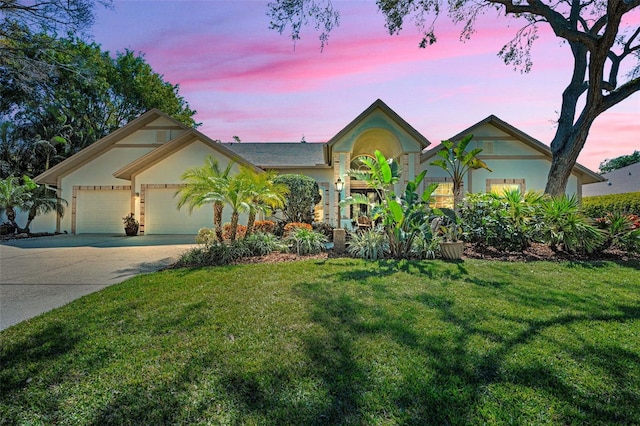 view of front facade with concrete driveway, a lawn, an attached garage, and stucco siding