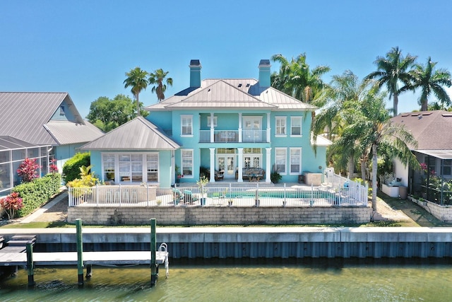 rear view of house featuring metal roof, a balcony, a water view, a standing seam roof, and a patio area