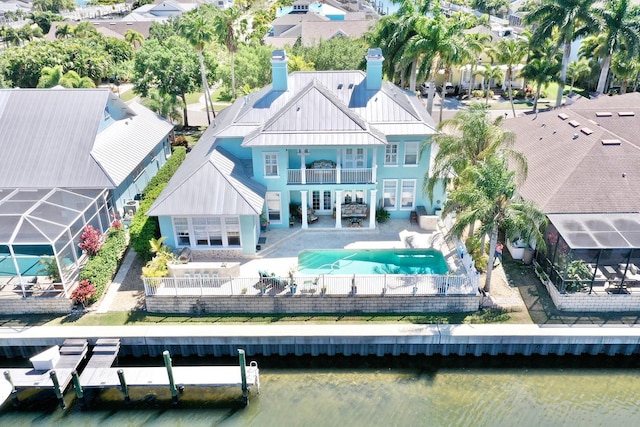 back of house featuring a hot tub, a patio, a balcony, a fenced backyard, and a chimney