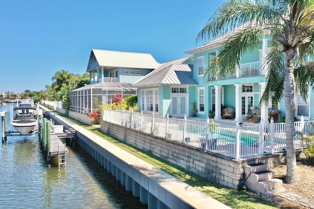 back of property featuring a patio, boat lift, a water view, french doors, and a fenced in pool