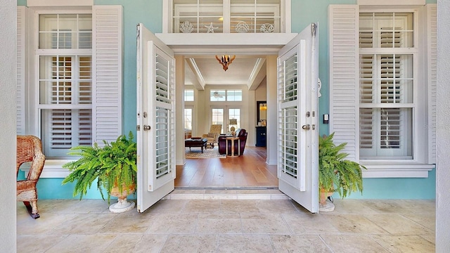 entrance foyer featuring ornamental molding, french doors, a chandelier, and stone finish flooring