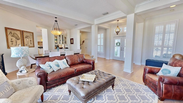 living area with plenty of natural light, light wood-style flooring, ornamental molding, and baseboards