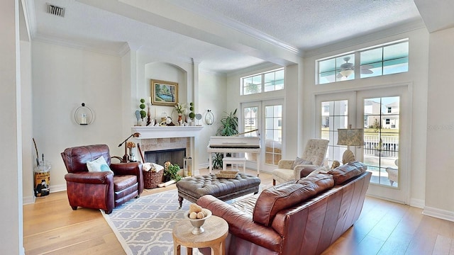 living room featuring french doors, visible vents, crown molding, and light wood finished floors