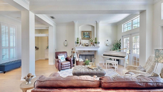 living area featuring crown molding, french doors, visible vents, and a fireplace