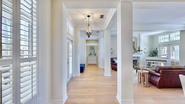 foyer entrance with baseboards, an inviting chandelier, crown molding, french doors, and light wood-type flooring