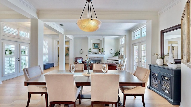 dining area featuring ornamental molding, french doors, plenty of natural light, and a fireplace