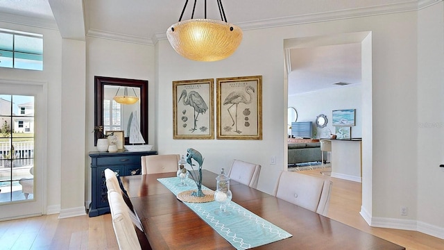 dining area with ornamental molding, light wood-type flooring, and baseboards