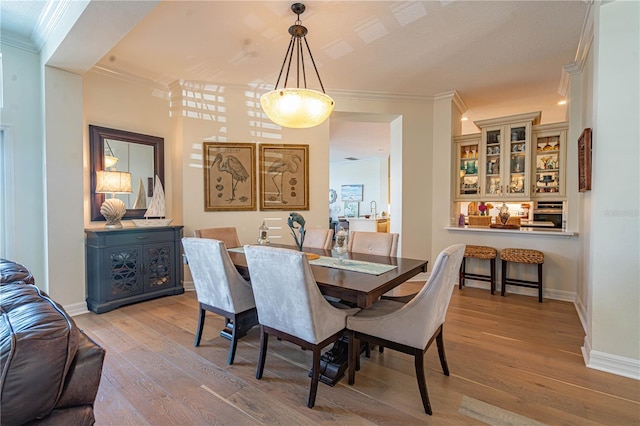 dining room featuring ornamental molding, hardwood / wood-style flooring, and baseboards